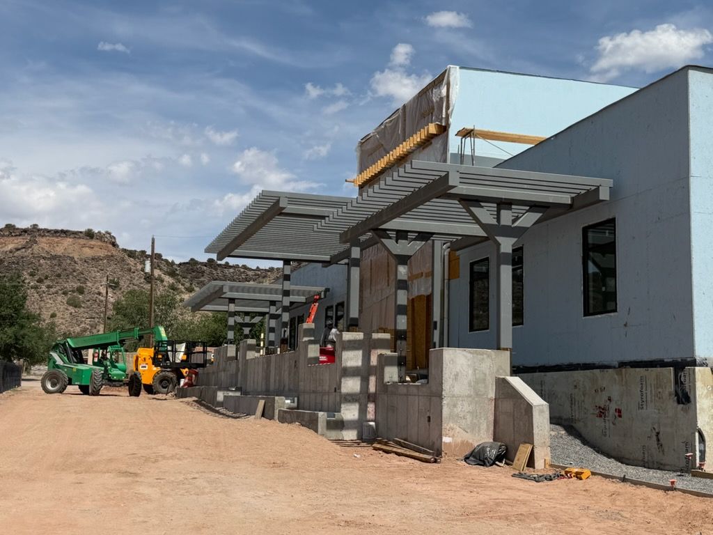 Steel-framed pergola structure under construction against the New Mexico high desert